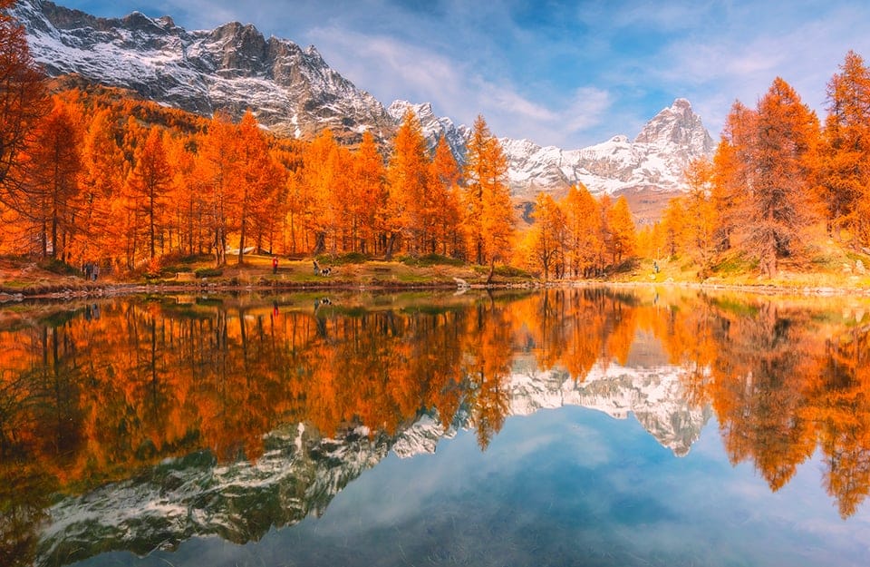 I riflessi degli alberi con le foglie rosse autunnali sul Lago Blu, a Cervinia, con sullo sfondo il monte Cervino