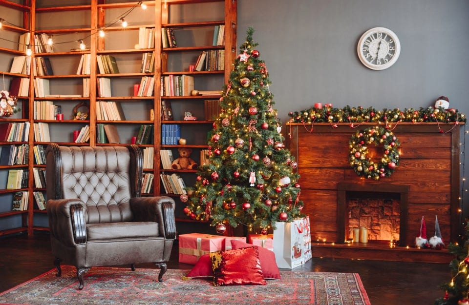 Un'accogliente salotto con camino, addobbato per il Natale, con luci, albero, regali, decorazioni e un tappeto orientale sotto l'albero