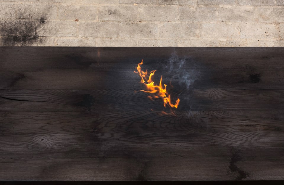 Delle fiamme sulla superficie di una tavola di legno che sta bruciando, durante il trattamento detto Yakisugi