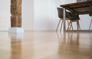 Visto a filo pavimento di un parquet lucido in una stanza con tavolo, sedie e antica colonna centrale in legno