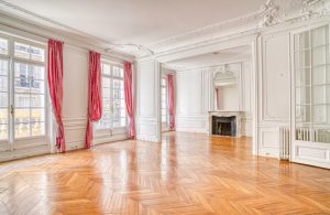 Ampia stanza di un palazzo d'epoca con parquet lucido, pareti e soffitti bianchi con stucchi e modanature