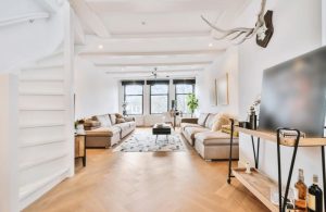 Luminoso salotto con pareti e soffitti bianchi, pavimento in parquet e arredo moderno che strizza l'occhio allo stile rustico
