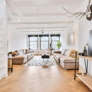 Luminoso salotto con pareti e soffitti bianchi, pavimento in parquet e arredo moderno che strizza l'occhio allo stile rustico