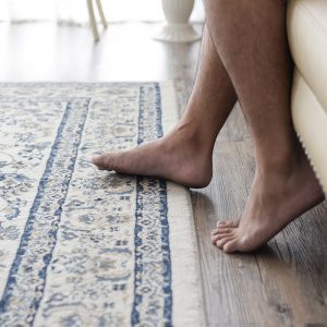 Perché il parquet scricchiola? Foto di piedi di uomo su tappeto e parquet