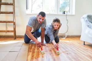 Uomo e donna verniciano il parquet