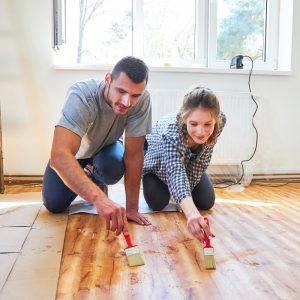 Uomo e donna verniciano il parquet