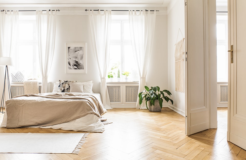 Una bianca e luminosa stanza da letto con parquet in acero