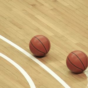 Due palloni da basket su un campo da gioco di parquet in acero
