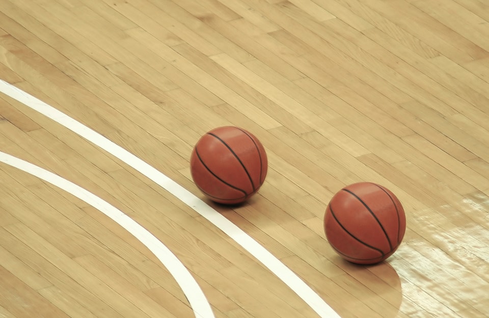 Due palloni da basket su un campo da gioco di parquet in acero