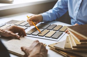 Dettaglio di un momento dell'acquisto di un parquet. Si vedono le mani di un venditore che mostra i campioni, e quelle di un cliente che sta ad ascoltare
