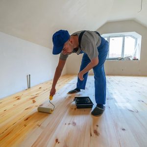 Posatore applica la finitura a un parquet in una mansarda