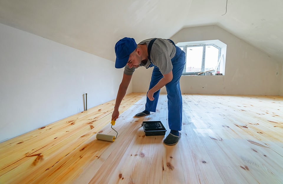 Posatore applica la finitura a un parquet in una mansarda