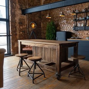Cucina open space in stile industriale, con parquet rustico, bancone in legno, sgabelli in metallo e legno, grandi finestre, pareti con mattoncini a vista