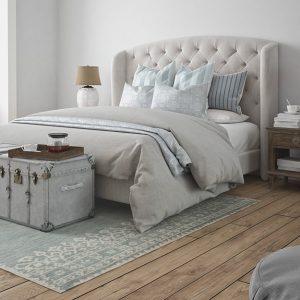 Camera da letto con parquet rustico. Sotto al letto c'è un grande tappeto, in fondo un due bauli, usati anche come tavolini da caffè. Accanto ai comodini ci sono pile di libri