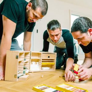 Tre uomini riparano le fessurazioni dei listoni di un parquet usando degli stick a cera