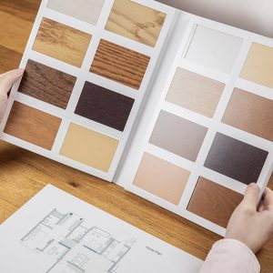 Una donna consulta un catalogo con le diverse essenze del parquet. Si vede anche la planimetria di un appartamento