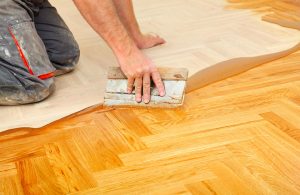 Un professionista applica con la spatola la finitura a un parquet