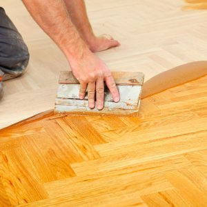 Un professionista applica con la spatola la finitura a un parquet