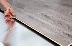 Un uomo posa un parquet a incastro sopra alle piastrelle