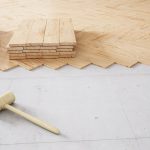 Posa di un parquet flottante su un pavimento preesistente. Si vede un martello in legno