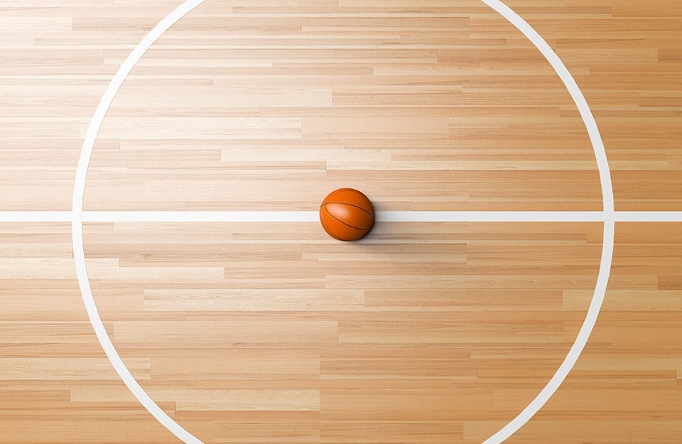 Centrocampo di un campo da basket visto dall'alto, con un pallone al centro esatto