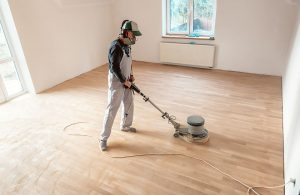 Un professionista leviga un parquet in una stanza vuota utilizzando l'apposita levigatrice