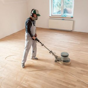 Un professionista leviga un parquet in una stanza vuota utilizzando l'apposita levigatrice