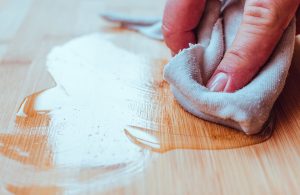 Una mano passa dell'olio sul parquet con un panno