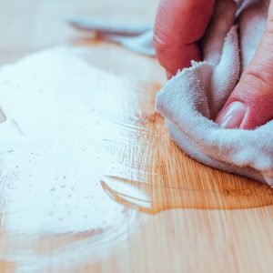 Una mano passa dell'olio sul parquet con un panno