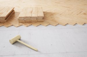 Posa di un parquet flottante su un pavimento preesistente. Si vede un martello in legno