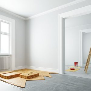 Stanza vuota e luminosa con un parquet parzialmente posato. Nell'altra stanza si intravede una scala