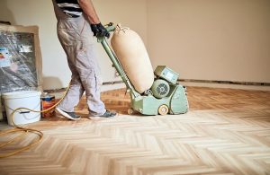 Un professionista si occupa della lamatura di un parquet usando una macchina levigatrice elettrica