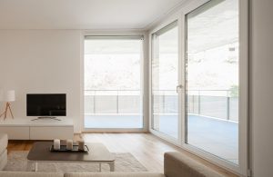 Salotto minimale e luminoso con grandi finestre che danno sull'esterno. Il parquet è in cabreuva incenso