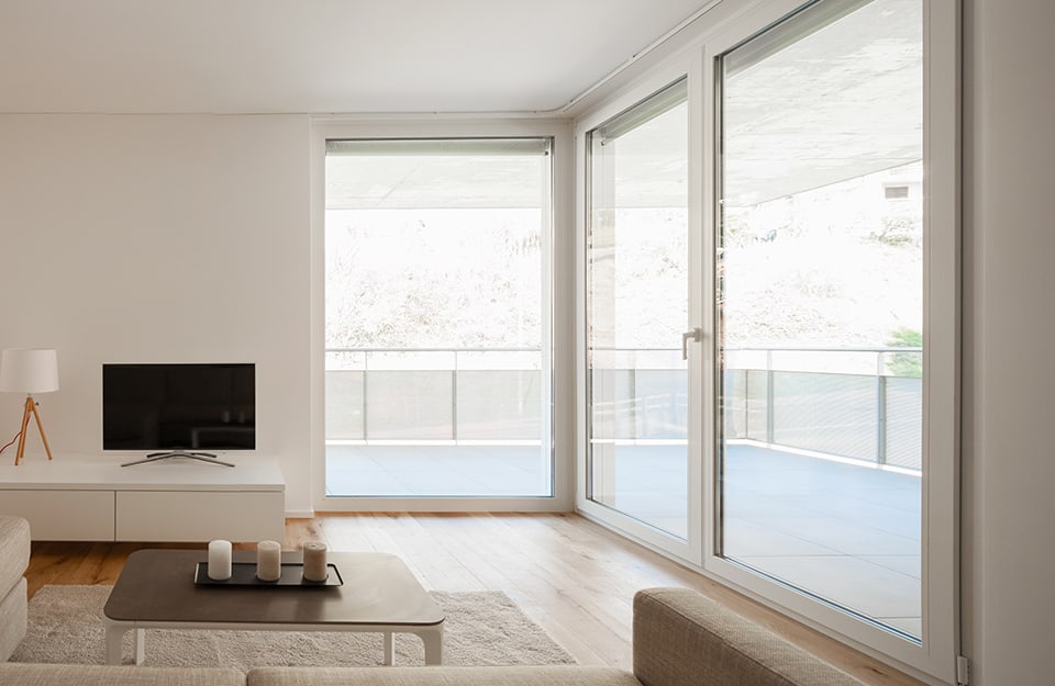 Salotto minimale e luminoso con grandi finestre che danno sull'esterno. Il parquet è in cabreuva incenso