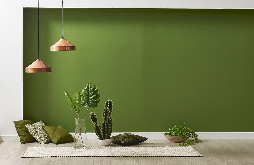 Angolo verde con parquet, tappeto, piante e lampadari color rame, secondo i principi del Feng Shui