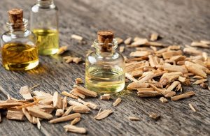Tre flaconi di olio essenziale di cedro, sopra un tavolo di legno in una composizione che vede anche la presenza di trucioli di legno di cedro