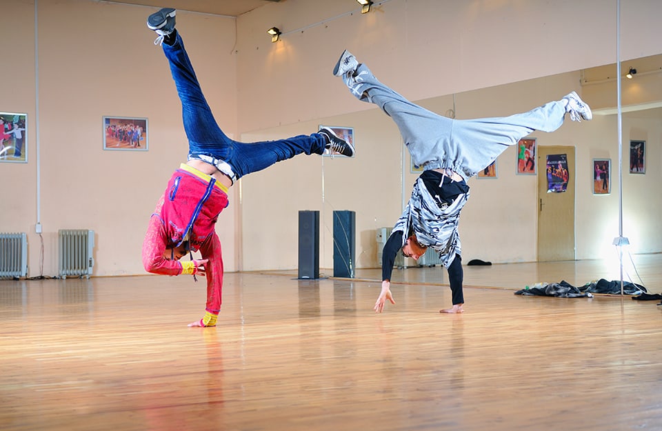 Due ballerini di danza moderna si allenano con evoluzioni a testa in già in una sala da ballo altrimenti vuota