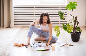 Una donna seduta sul parquet progetta la disposizione degli arredi seguendo i principi del Feng Shui