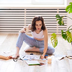 Una donna seduta sul parquet progetta la disposizione degli arredi seguendo i principi del Feng Shui