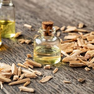 Tre flaconi di olio essenziale di cedro, sopra un tavolo di legno in una composizione che vede anche la presenza di trucioli di legno di cedro