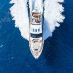 Vista dall'alto su uno yacht che sfreccia sull'acqua lasciandosi dietro una scia di schiuma