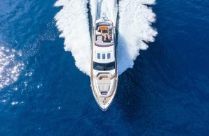 Vista dall'alto su uno yacht che sfreccia sull'acqua lasciandosi dietro una scia di schiuma