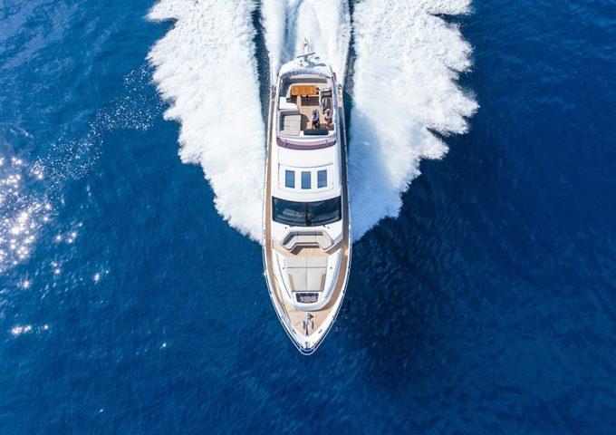 Vista dall'alto su uno yacht che sfreccia sull'acqua lasciandosi dietro una scia di schiuma
