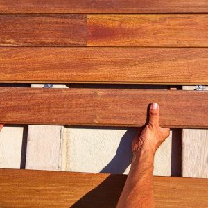 Le mani di un operaio sistemano le assi di legno ipe per il decking