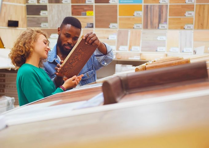 Un uomo e una donna in uno showroom di parquet scelgono l'essenza per il loro pavimento in legno