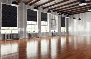Un ampio spazio industriale ristrutturato con molti grandi finestroni e parquet scuro e molto lucido