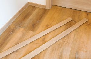 Due singole assi di battiscopa poggiate su un parquet