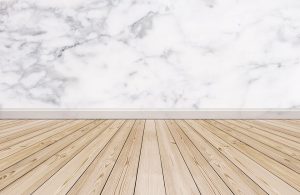 Un parquet in legno abbinato a una parete in marmo con battiscopa pure in marmo