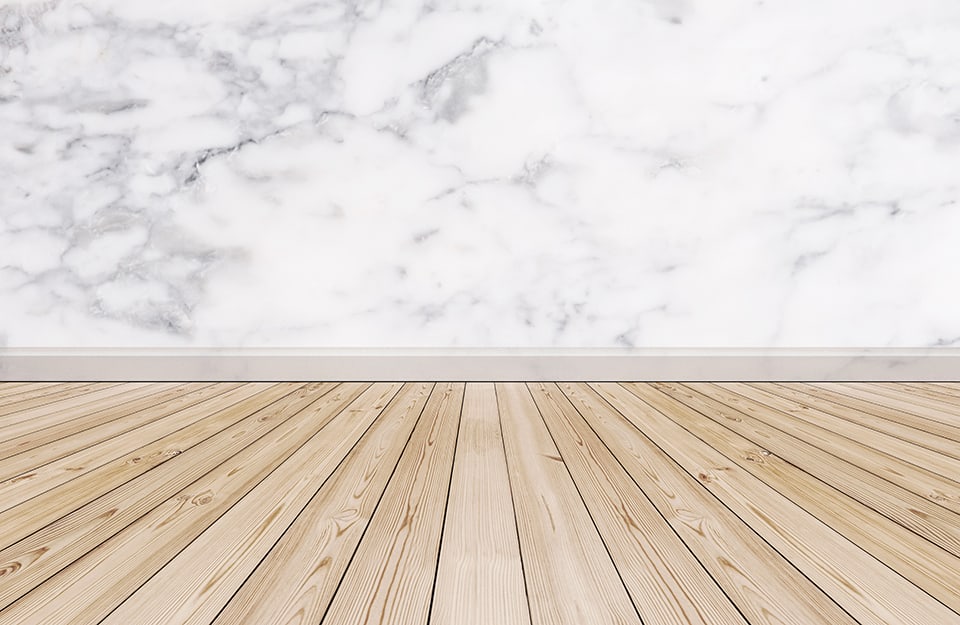 Un parquet in legno abbinato a una parete in marmo con battiscopa pure in marmo