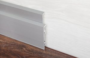 Dettaglio di un battiscopa in alluminio su un parquet in legno scuro